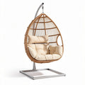 Hanging egg chair with beige cushion and steel stand for outdoor use
